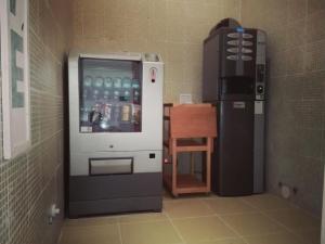 un distributore di bevande in una stanza accanto a un tavolo di Birilli B&B a Civitanova Marche