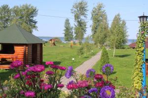 a garden with flowers and a wooden cabin at Hotel-complex Mizh Triokh Ozer in Svityazʼ