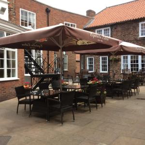 a group of tables and chairs with umbrellas at The Golden Lion Hotel in Northallerton