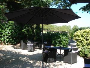 een zwarte paraplu naast een tafel en stoelen bij Relais du Château in Saint-Blancard