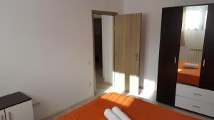 ポイアナ・ブラショフにあるApartament Andraのベッドルーム(オレンジ色のソファ、鏡付)