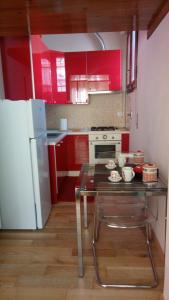 ボローニャにあるMonolocale Bolognaのキッチン(赤いキャビネット、テーブル、冷蔵庫付)