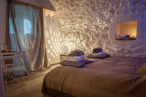 - une chambre avec un lit dans une pièce dotée d'un mur en pierre dans l'établissement Via Roma 75 mini sweet suite, à Ostuni