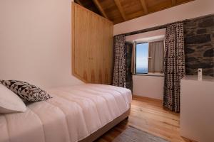a bedroom with a large bed and a window at Casa do Leme in Arco da Calheta