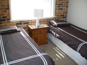 two beds in a room with a lamp and a window at Mainsail 10 17 Owen Street in Port Macquarie