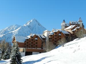 a hotel in the snow with a mountain in the background at Hotel Le Cairn in Les Deux Alpes