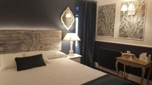1 dormitorio con 1 cama y 1 mesa con lámpara en Hotel Boutique Balaitus, en Sallent de Gállego