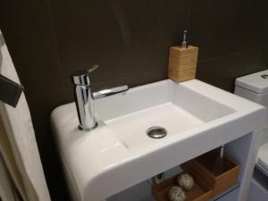 a white sink in a bathroom next to a toilet at Ah33 - Estúdios in Coimbra