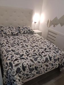 Schlafzimmer mit einem Bett mit einer schwarzen und weißen Bettdecke in der Unterkunft Bonito Apto Barrio del Pilar Smart Fit in Madrid
