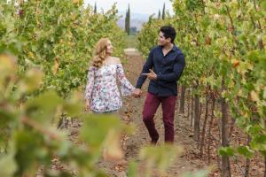 a couple walking through a vineyard holding hands at El Cielo Resort in Valle de Guadalupe