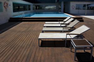 a row of lounge chairs sitting on a deck next to a swimming pool at Thalasia Costa de Murcia in San Pedro del Pinatar