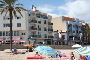 people on a beach with umbrellas and a hotel at Hotel Mare Nostrum in Peniscola