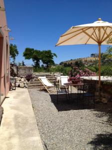 a patio with an umbrella and chairs and a table at BioAgriturismo Antica Sena in Milici