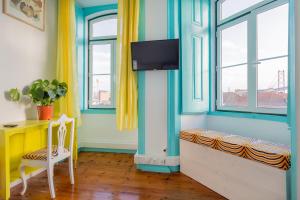 um quarto com uma secretária, janelas e uma televisão em C&O Guest House Lisbon em Lisboa
