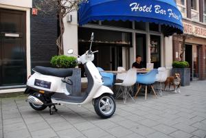 un scooter garé devant un restaurant avec une femme assise à une table dans l'établissement Frisco Inn, à Amsterdam