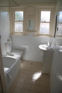 a white bathroom with a tub and a toilet and a sink at Accommodation Sydney Rockdale - 2 Bedroom Pet Friendly Budget Apartments near Rockdale Station and Brighton Le Sands Beach in Sydney +17 photos