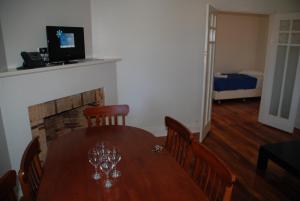 a dining room with a wooden table with wine glasses on it at Accommodation Sydney Rockdale in Sydney