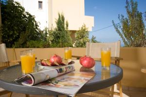 een tafel met een schaal fruit en twee glazen sinaasappelsap bij Aloni Villas in Roussospítion