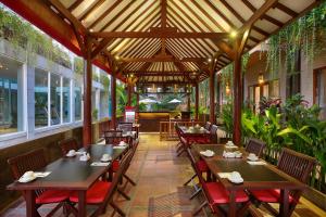 a restaurant with wooden tables and chairs and plants at Bali Chaya Hotel Legian in Legian