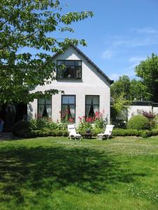 una casa blanca con 2 sillas en el patio en de Witte Wolk, en Nieuw-Scheemda