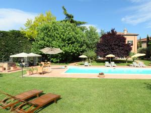 a swimming pool with chairs and umbrellas in a yard at Villa Paolotti by Interhome in Bettona