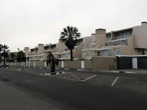 pusta ulica z palmami przed budynkiem w obiekcie Sand & Sea Self-Catering Apartments w mieście Swakopmund