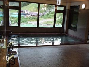 a pool of water in a bathroom with windows at Onsen Hotel Itakura in Yamanouchi