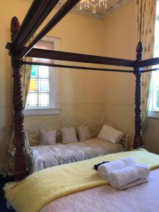 two beds in a bedroom with a canopy bed at Hall on the Terrace in Temuka
