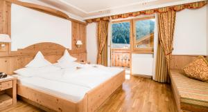 a bedroom with a large bed and a large window at Hotel Dorfer Alpine&Charming in Selva di Val Gardena