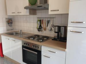 eine Küche mit weißen Schränken und einem Herd mit Backofen in der Unterkunft Ferienwohnung Rosi Stoppa in Burg + 11 Fotos