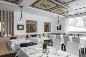 a dining room with white tables and white chairs at Hotel Conturines in San Cassiano