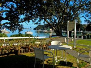 Hananui Lodge and Apartments في راسيل: طاولة وكراسي في حديقة مطلة على الماء