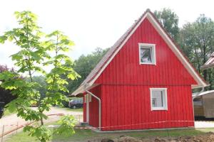 czerwona stodoła z białym oknem na dziedzińcu w obiekcie Wald- und Seeblick Camp Zislow w mieście Zislow
