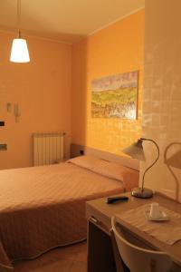 ein Schlafzimmer mit einem Bett und einem Schreibtisch mit einer Lampe in der Unterkunft B&B al Castello Torremaggiore in Torre Maggiore