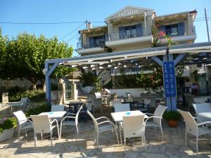 un restaurant avec des tables et des chaises blanches en face d'un bâtiment dans l'établissement Boutique Hotel Iasmos, à Trizonía