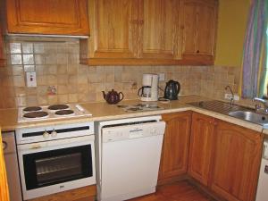 a kitchen with wooden cabinets and a white stove top oven at Holiday Home Seaside Cottages-1 in Valentia Island