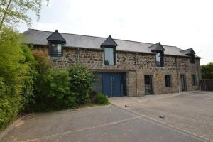 a brick building with a blue door and a driveway at Entre St Malo et Rennes à Becherel in Bécherel