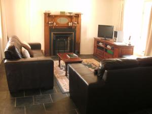 sala de estar con 2 sofás y TV en Peppermint Farm Cottage, en McLaren Vale