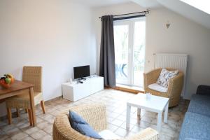 a living room with a couch and chairs and a tv at Haus Anker in Sankt Peter-Ording