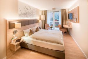 ein Schlafzimmer mit großem Bett und Schreibtisch in der Unterkunft Hotel Altes Zollhaus in Horumersiel
