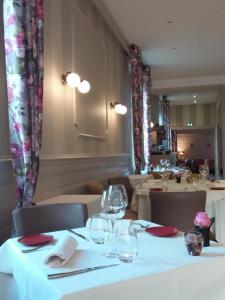 un restaurant avec des tables et des chaises blanches et des verres à vin dans l'établissement Hostellerie d'Héloïse, à Cluny