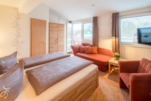 Zimmer mit 2 Betten, einem Sofa und einem TV in der Unterkunft Hotel Altes Zollhaus in Horumersiel