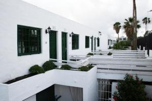 a white building with green shuttered windows and stairs at Apartamentos Guanarama in Puerto del Carmen