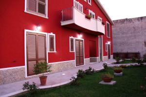 a red building with windows and plants in a yard at Il Quadrifoglio in Trapani