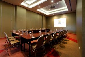 Hotel Gunawangsa MERR في سورابايا: قاعة اجتماعات كبيرة مع طاولة وكراسي طويلة