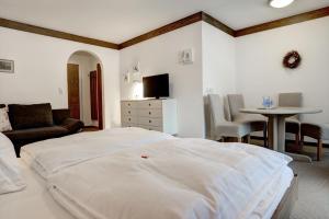 a bedroom with a white bed and a table and chairs at Pension Forsthof in Maishofen