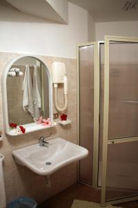 een badkamer met een wastafel, een douche en een spiegel bij Hotel L'Ancora in Capo Vaticano