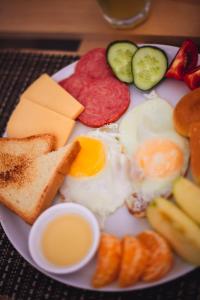 a plate of breakfast food with eggs bacon cheese and toast at Aktau Hotel in Aktau