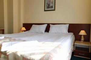 um quarto com uma cama grande e lençóis brancos em Hotel Aleksander em Ustka