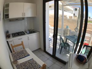 uma pequena cozinha com vista para uma mesa e cadeiras em Appartamento sul mare em Noto Marina